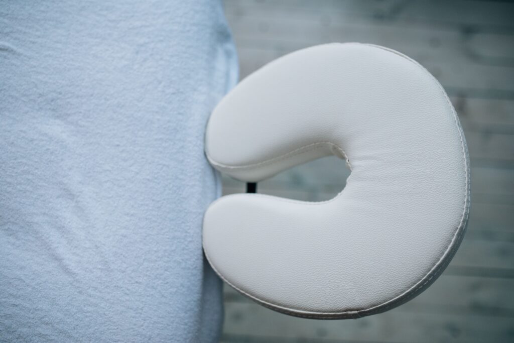 Minimalistic top view of a massage table with a white headrest cushion for relaxation.